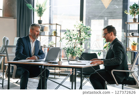 Two men is working on the project. Business people are together in the office Two men is working on the project. Business people are together in the office 127372626