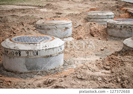 Construction site with newly installed concrete manholes in preparation for utility installation Construction site with newly installed concrete manholes in preparation for utility installation 127372688