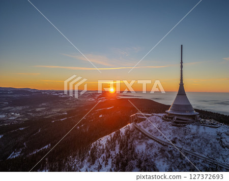 Stunning sunrise illuminates Jested Mountain, casting warm hues over a snowy landscape. The quiet beauty of winter contrasts with the vibrant sky as day breaks over the horizon. Stunning sunrise illuminates Jested Mountain, casting warm hues over a snowy landscape. The quiet beauty of winter contrasts with the vibrant sky as day breaks over the horizon. 127372693