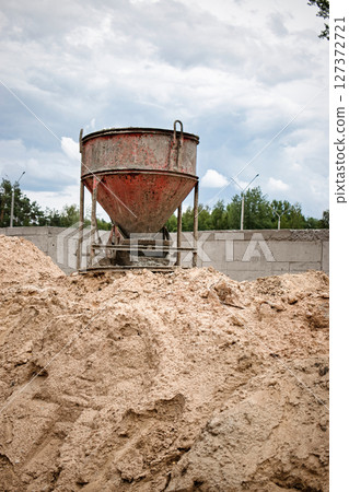 Construction site with concrete mixer and sand pile under cloudy sky Construction site with concrete mixer and sand pile under cloudy sky 127372721