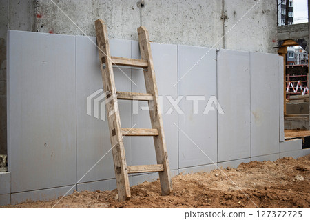 Wooden ladder against unfinished wall at construction site in urban area during daytime Wooden ladder against unfinished wall at construction site in urban area during daytime 127372725