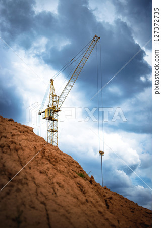 Construction crane working against a dramatic sky at a building site during the afternoon 127372735