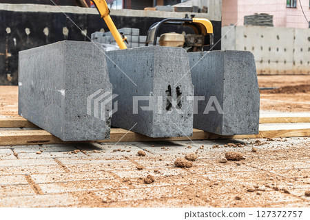 Concrete blocks lined up on construction site in urban area during daylight for building foundation preparation Concrete blocks lined up on construction site in urban area during daylight for building foundation preparation 127372757