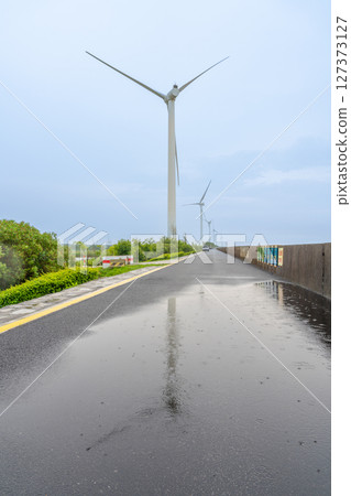 Wind turbines in the rain and reflections of water on the ground 127373127