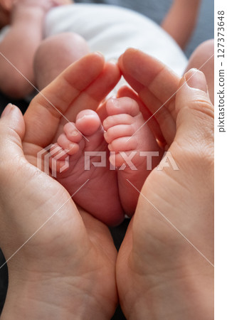 Tender Moment: Adult Hands Holding Newborn Baby Feet 127373648