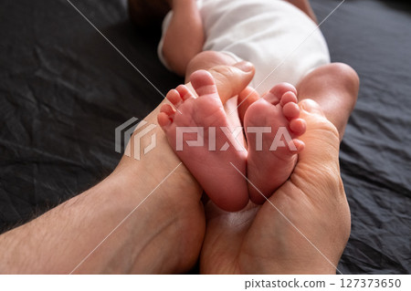 Tender Moment: Adult Hands Holding Newborn Baby Feet 127373650