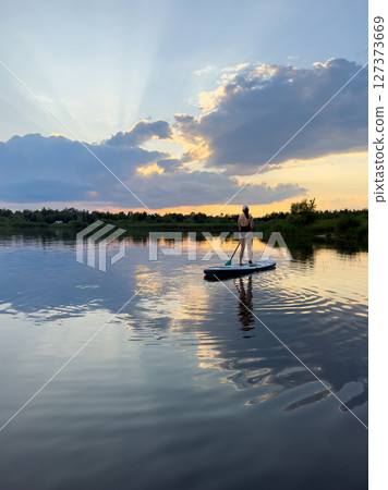 Paddleboarding at Sunset on a Tranquil Lake 127373669