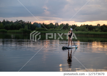 Paddleboarding at Sunset on a Tranquil Lake 127373670