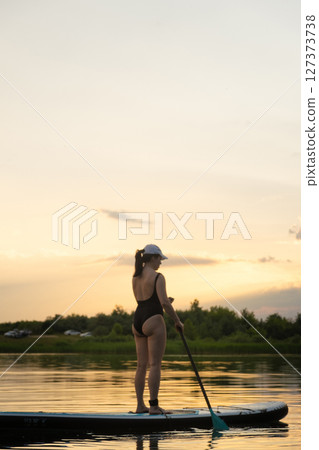 Paddleboarding at Sunset on a Tranquil Lake 127373738