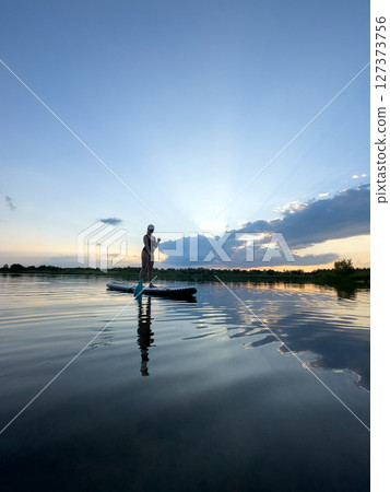 Paddleboarding at Sunset on a Tranquil Lake Paddleboarding at Sunset on a Tranquil Lake 127373756