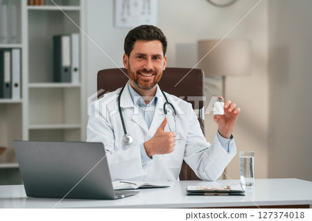 Holding pills. Doctor in formal clothes is working in the cabinet Holding pills. Doctor in formal clothes is working in the cabinet 127374018