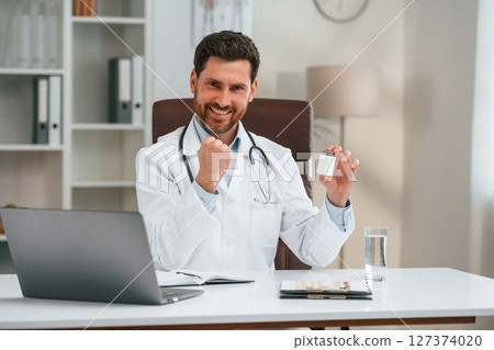 With medicine. Doctor in formal clothes is working in the cabinet 127374020