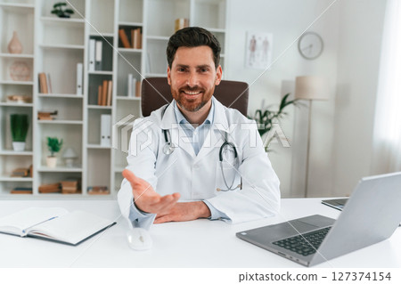 Sitting by a table. Doctor in formal clothes is working in the cabinet 127374154