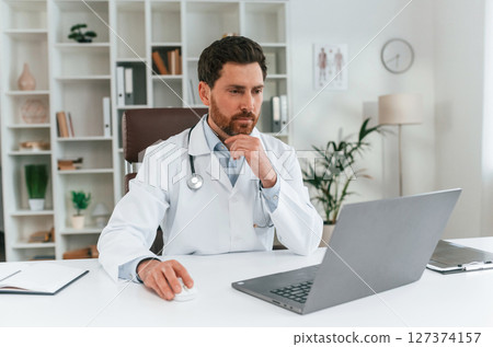 Sitting by a table. Doctor in formal clothes is working in the cabinet Sitting by a table. Doctor in formal clothes is working in the cabinet 127374157