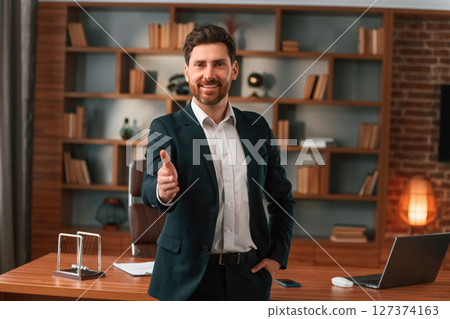 Greetings, giving the hand. Businessman in formal clothes is working indoors Greetings, giving the hand. Businessman in formal clothes is working indoors 127374163