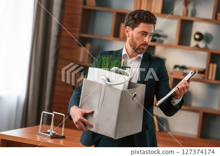 With a box of stuff in it. Businessman in formal clothes is working indoors 127374174