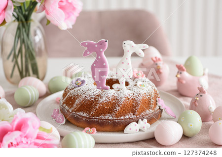 Traditional easter cakes with icing decorated with gingerbread cookies in shape of rabbits on white wooden table Traditional easter cakes with icing decorated with gingerbread cookies in shape of rabbits on white wooden table 127374248