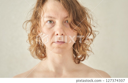 Caucasian adult female with curly hair staring directly at camera against 127374307