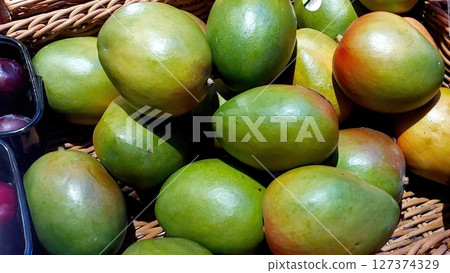 Fresh Mangoes Displayed in a Wicker Basket at a Local Market During a Sunny Afternoon Fresh Mangoes Displayed in a Wicker Basket at a Local Market During a Sunny Afternoon 127374329