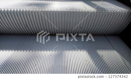 Sleek and Modern Escalator Stairs With Sunlight Casting Shadows in a Public Space Sleek and Modern Escalator Stairs With Sunlight Casting Shadows in a Public Space 127374342