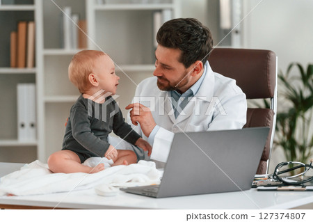 Doctor with little baby is working in the cabinet Doctor with little baby is working in the cabinet 127374807