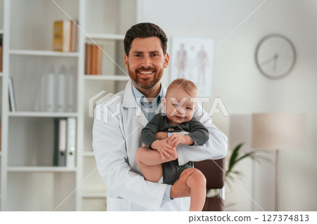 Holding boy in hands. Doctor with little baby is working in the cabinet 127374813