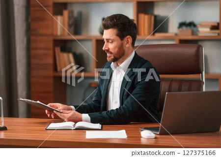 Working with documents. Businessman in formal clothes is indoors Working with documents. Businessman in formal clothes is indoors 127375166
