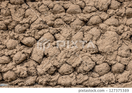Rustic hand-formed adobe lumps wall texture in rural outdoor setting Rustic hand-formed adobe lumps wall texture in rural outdoor setting 127375389