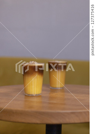 two glasses of coffee with orange juice on the table in a cafe 127375416