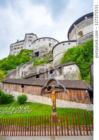 Visitors admire the impressive Kufstein Fortress, which stands atop a hill surrounded by lush greenery. The medieval architecture contrasts with the cloudy sky, creating a striking view. Visitors admire the impressive Kufstein Fortress, which stands atop a hill surrounded by lush greenery. The medieval architecture contrasts with the cloudy sky, creating a striking view. 127375531