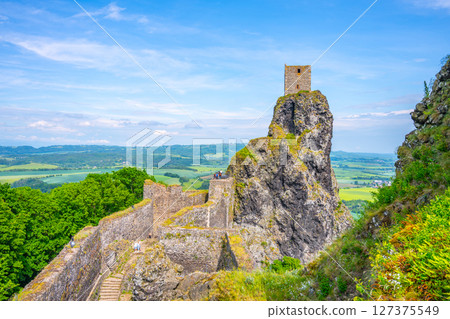 Visitors admire the stunning views from Panna Tower, situated atop a rocky cliff at Trosky Castle Ruins. The lush green landscapes of Bohemian Paradise stretch far and wide. 127375549