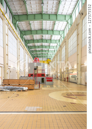 Expansive interior of Orlik Hydroelectric Power Station in Czechia showcases industrial architecture with large windows, tiles, and machinery. 127375552