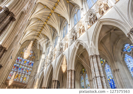 Discover the intricate gothic architecture of Westminster Abbey, featuring stunning arches, detailed stained glass windows, and splendid chandeliers that illuminate the historic interior. 127375563