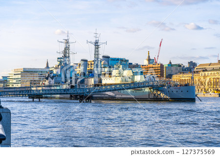 HMS Belfast is docked on the River Thames in London, showcasing its iconic structure against a backdrop of urban architecture and blue skies. Visitors can learn about its naval history. HMS Belfast is docked on the River Thames in London, showcasing its iconic structure against a backdrop of urban architecture and blue skies. Visitors can learn about its naval history. 127375569