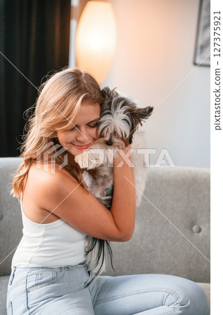 Beautiful young woman is with little dog indoors 127375921