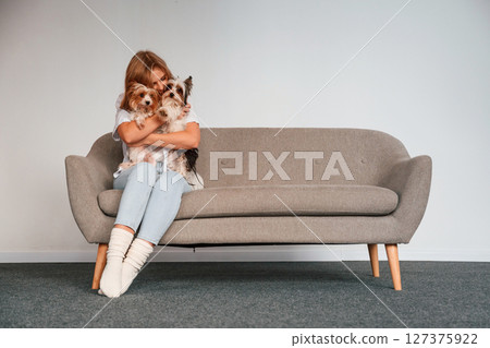 Conception of care and love. Woman is sitting on a sofa with two cute dogs 127375922