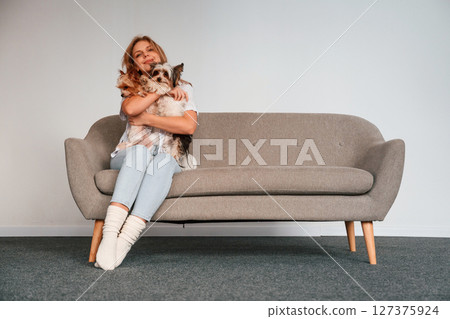 Conception of care and love. Woman is sitting on a sofa with two cute dogs 127375924
