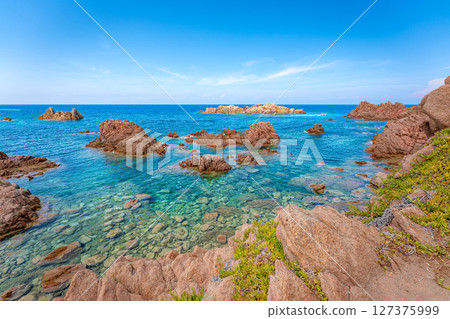 Rocky coastline meets crystal-clear turquoise water, creating a serene seascape. Sardinia 127375999