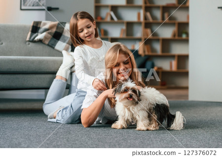 On the floor. Mother with her daughter and with cute dog is in domestic room 127376072