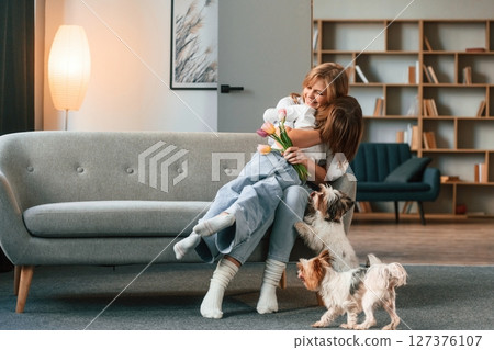 In domestic room. Mother with her daughter and with two cute dogs 127376107