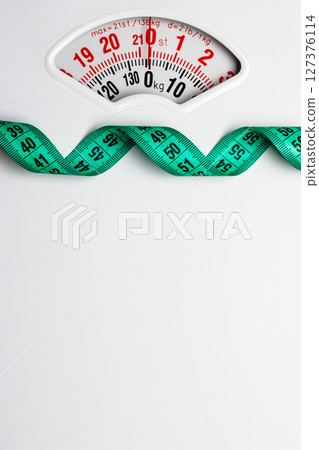 Green measuring tape on weight scale. Dieting 127376114