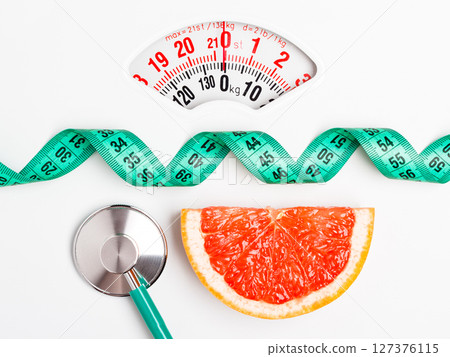 Grapefruit with measuring tape on weight scale. Dieting 127376115