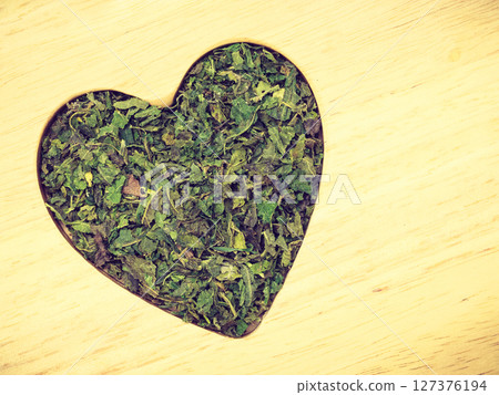 Dried nettle leaves heart shaped on wooden surface 127376194