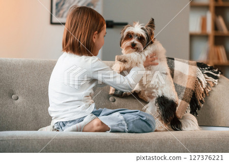 Playing on the sofa. Little girl is at home with cute dog Playing on the sofa. Little girl is at home with cute dog 127376221