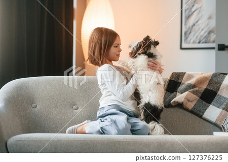 Sitting on the sofa. Little girl is at home with cute dog Sitting on the sofa. Little girl is at home with cute dog 127376225