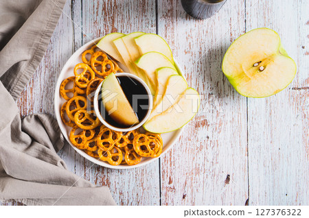 Delicious miso caramel dipping sauce, granny smith apples and pretzels on a plate top view 127376322