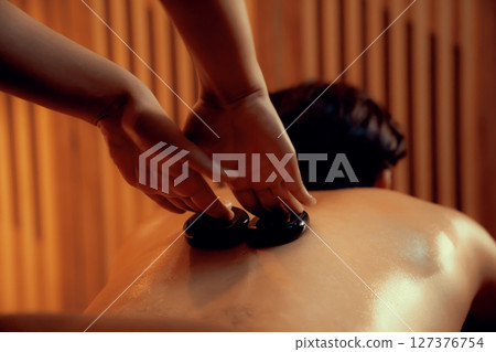 Hot stone massage at spa salon in luxury resort with warm candle light.Quiescent Hot stone massage at spa salon in luxury resort with warm candle light.Quiescent 127376754