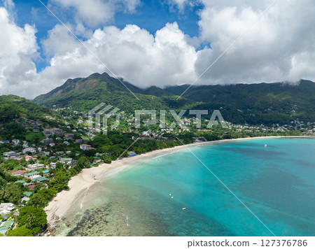 Curved sandy beach with mountainous surroundings, crystal clear waters and gentle waves. Seychelles, Mahe. Beau Vallon Beach. 127376786