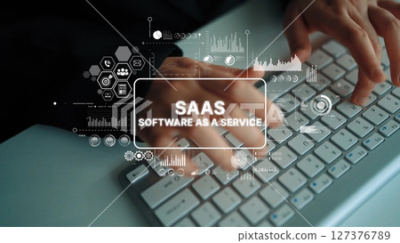 Hands Typing on Keyboard with Graphics Representing SaaS Concepts and Digital Technology in Office Environment. Asymptotic smart data analytic 127376789