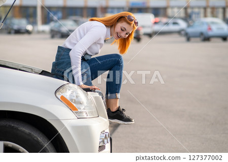 Young stressed woman driver near broken car with popped hood waiting for assistance. Young stressed woman driver near broken car with popped hood waiting for assistance. 127377002